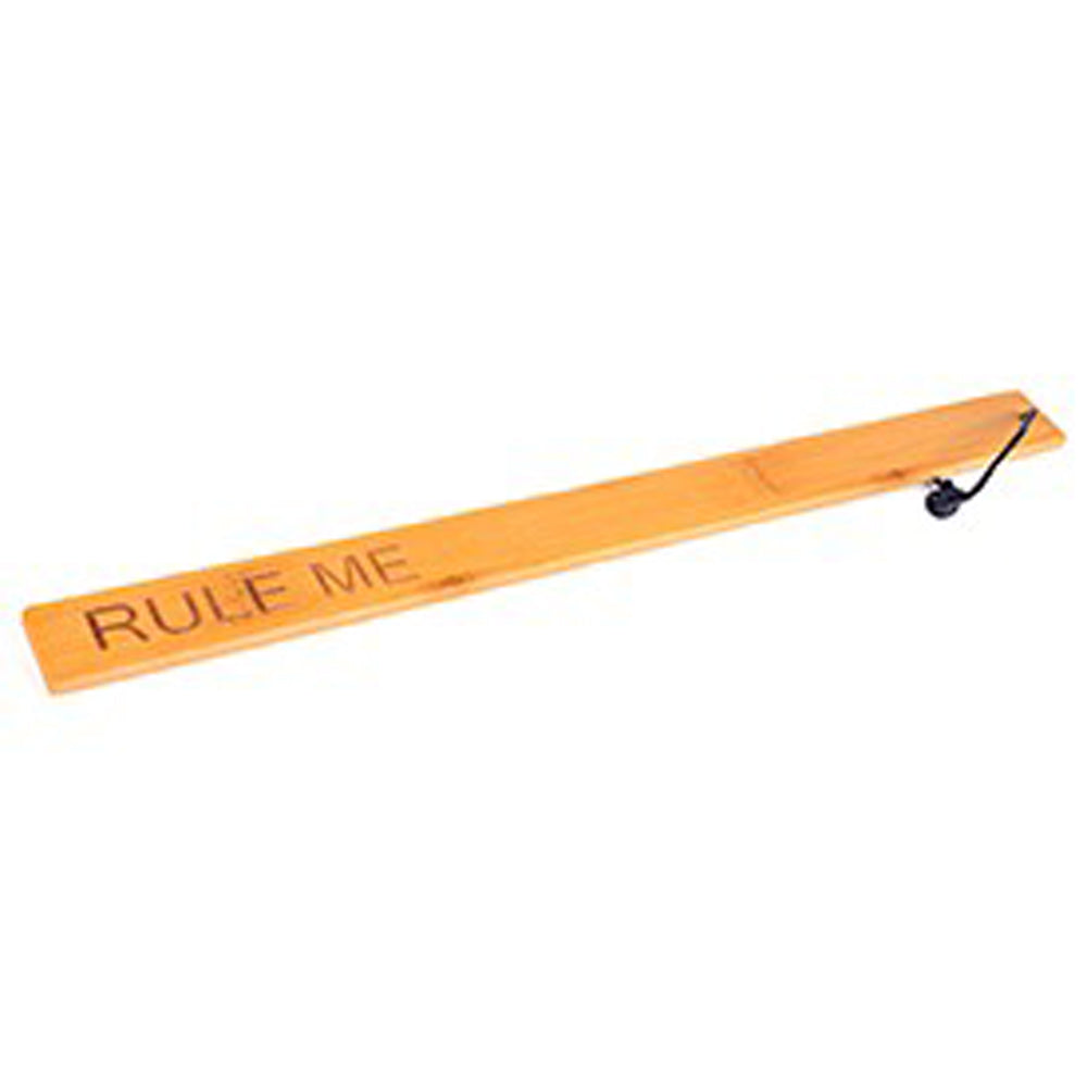 Bamboo paddle ruler with "RULE ME" text and a black cord.