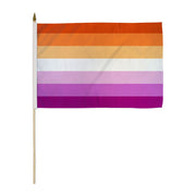 A Lesbian Sunset stick flag with orange, white, and pink stripes on a wooden stick.