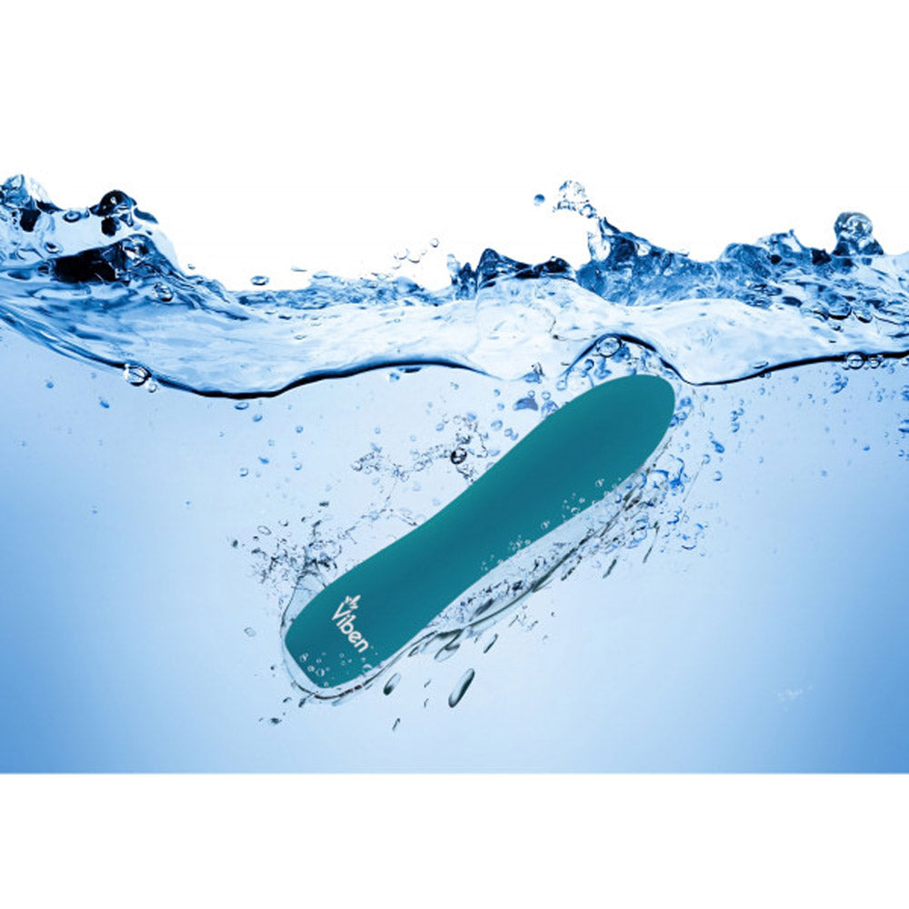 Teal silicone bullet vibrator submerged in water with splashes.