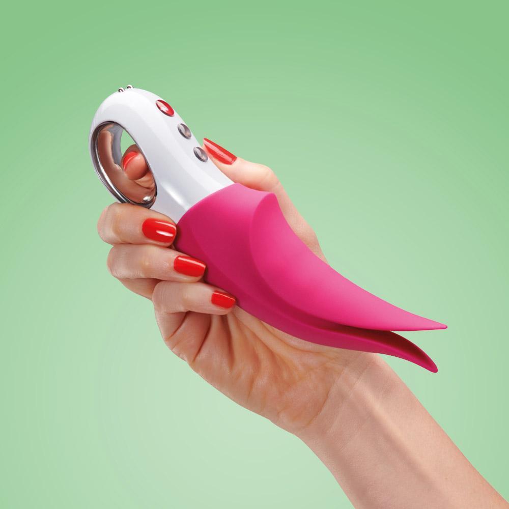 A hand holds a pink and white clitoral vibrator with tapping tips.