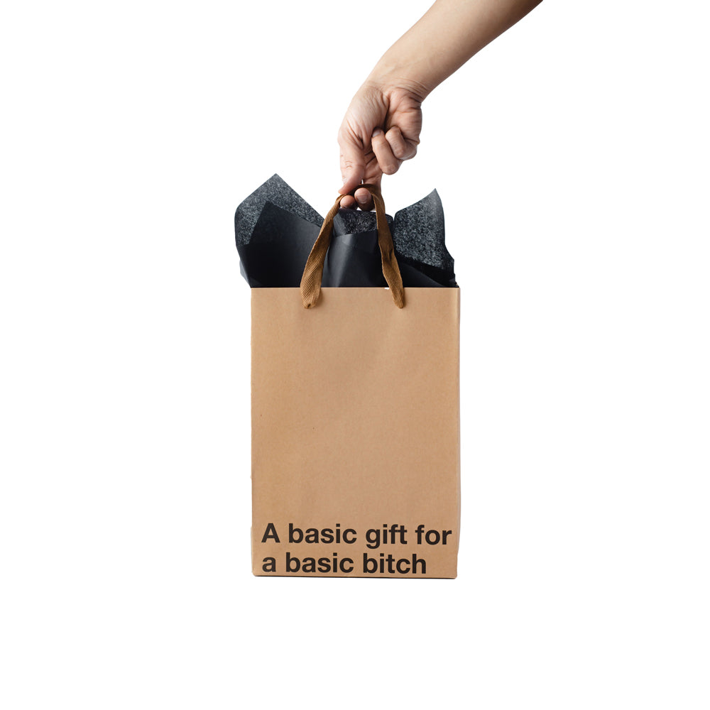 A brown paper gift bag with black tissue paper and the text "A basic gift for a basic bitch".