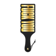 Black spanking paddle with gold "Fuck You" text and a hanging strap.