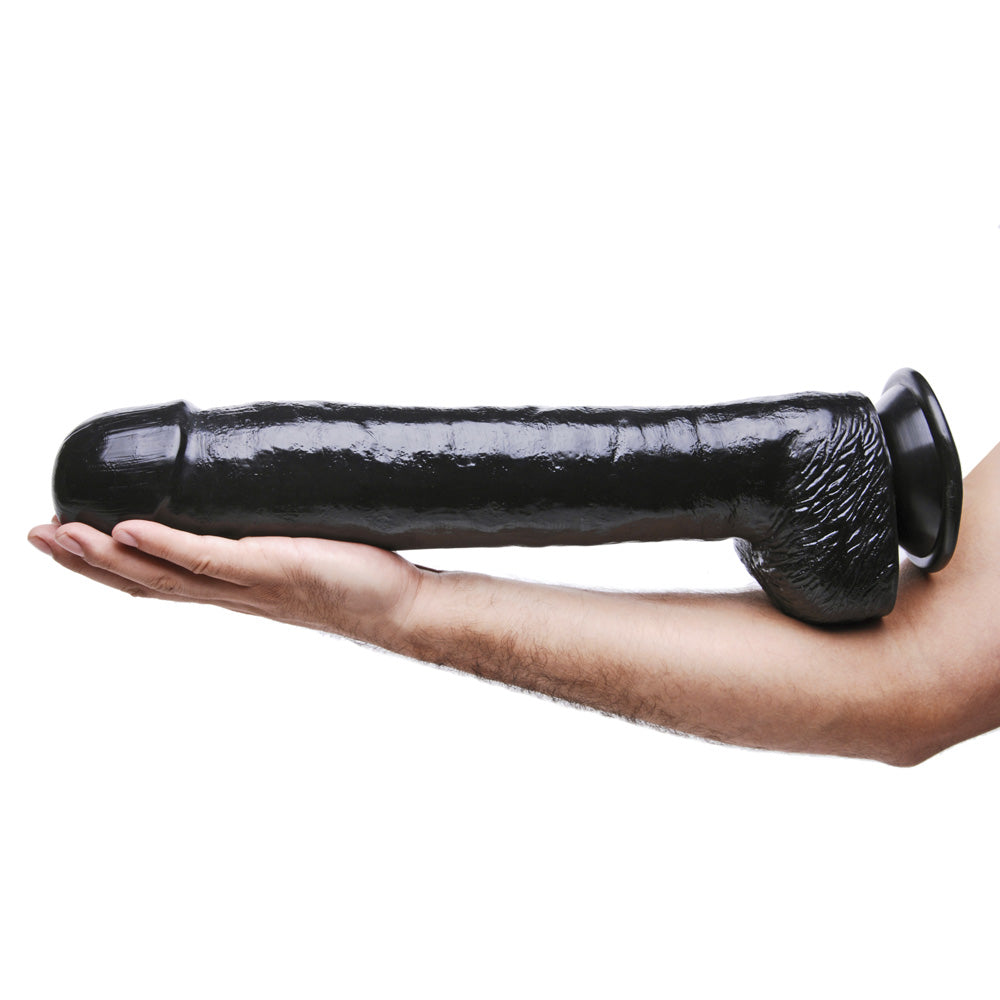 A large black PVC dildo with a textured base held in a hand.