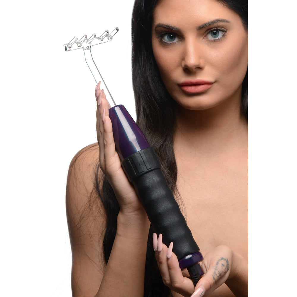 A woman holds a violet and black violet wand with five glass electrodes.
