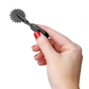 Black ABS mini sensation pinwheel with spiked wheel held in a hand.