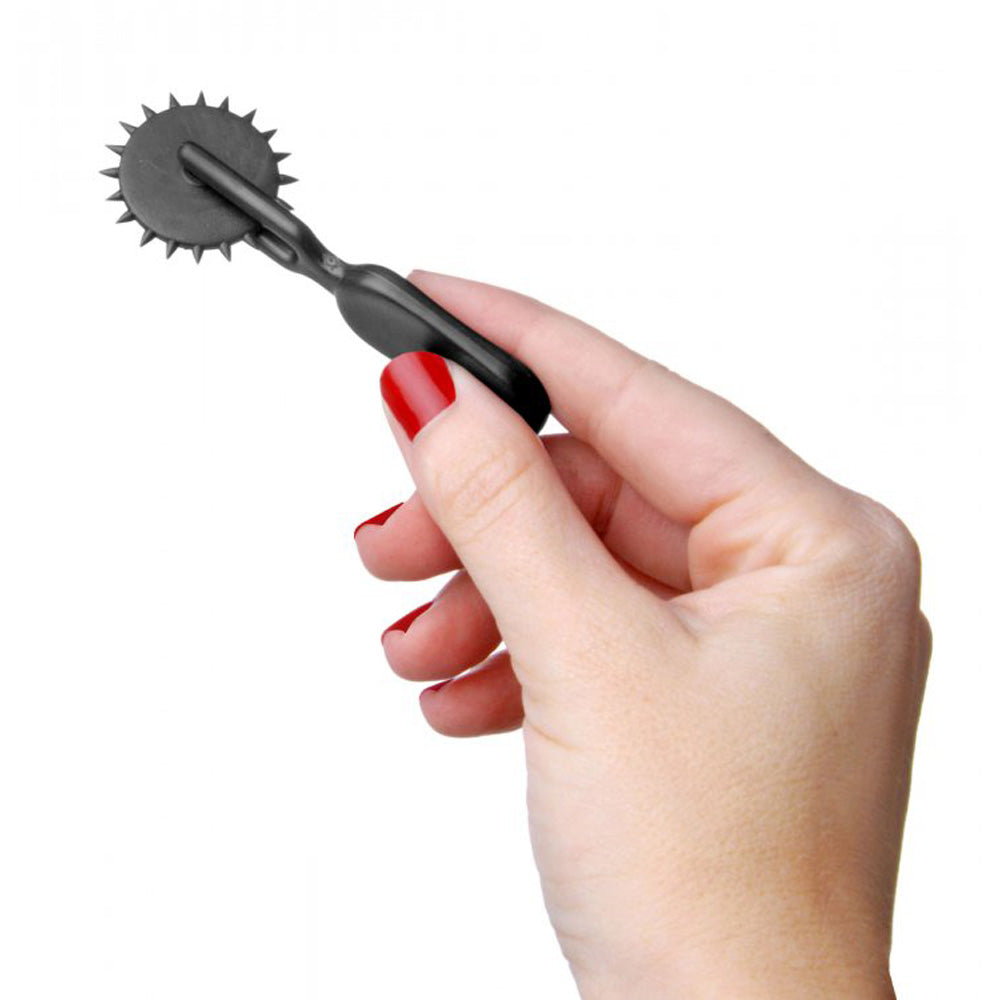 Black ABS mini sensation pinwheel with spiked wheel held in a hand.