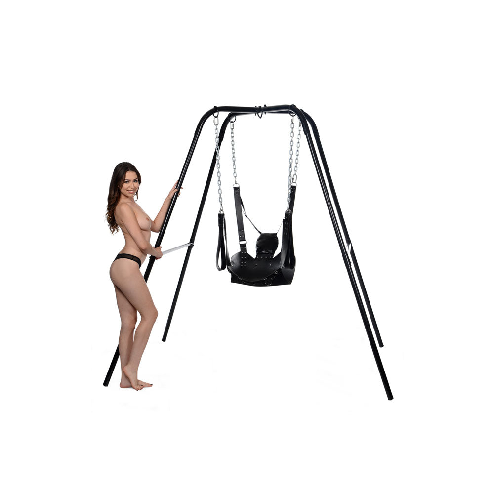Black leather bondage sling with stirrups and pillow on a metal frame.