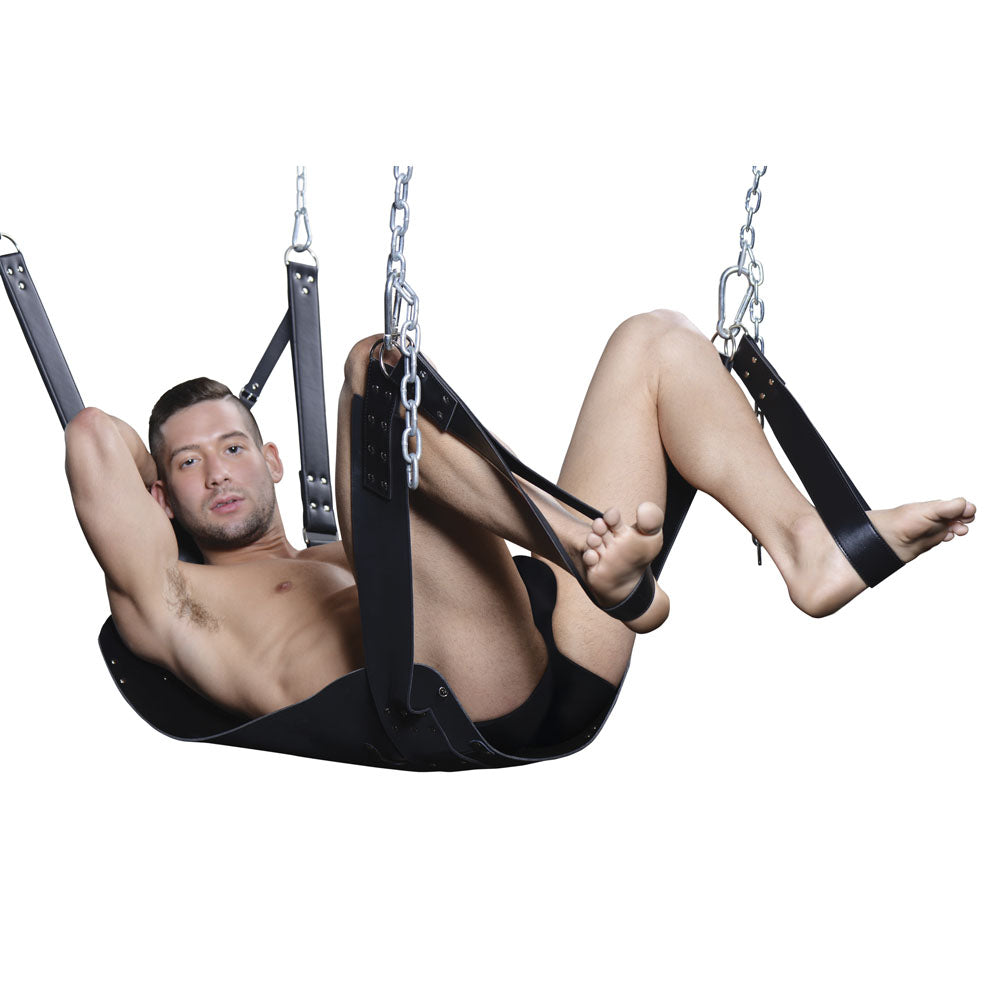 Man in a black leather bondage sling with stirrups and chains.
