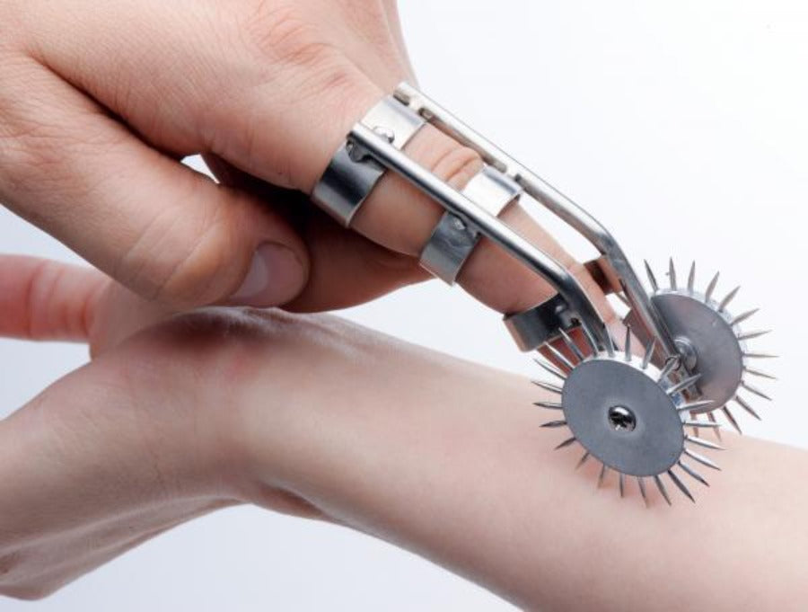 Metal finger ring with two spiked wheels for sensation play.