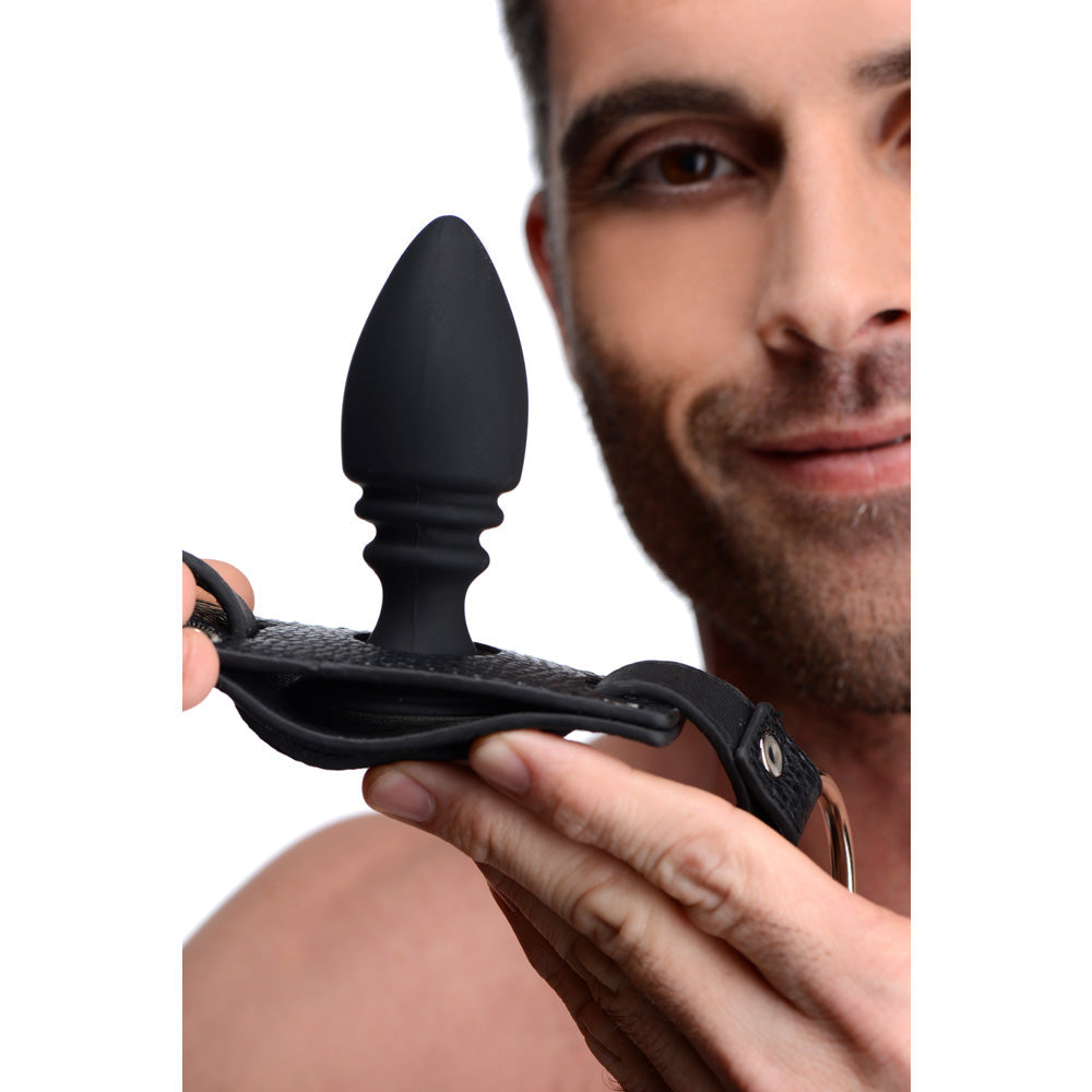 Black silicone anal plug with a leather harness and metal ring.