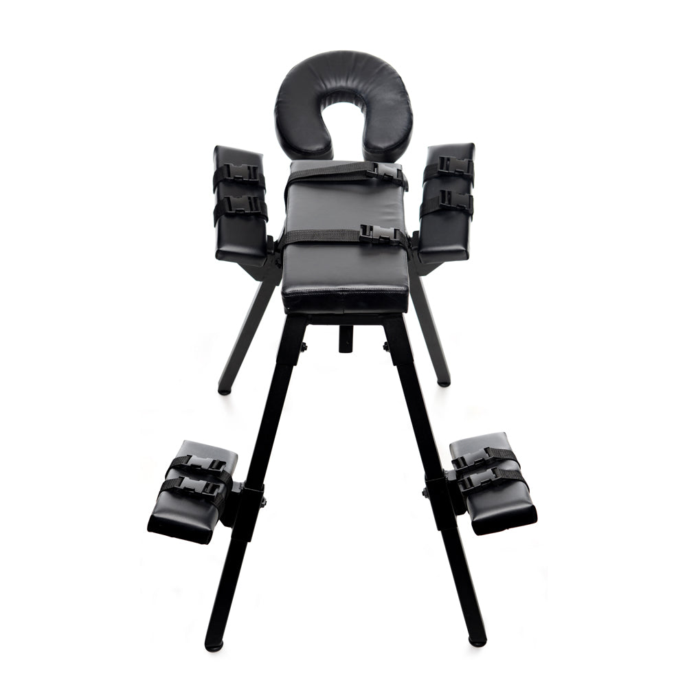 Black steel sex bench with padded restraints and headrest.