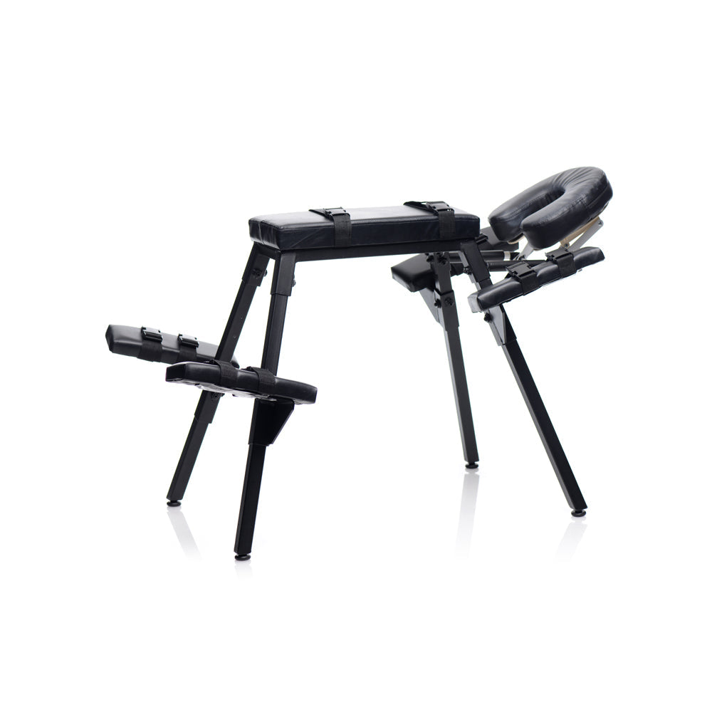 Black steel frame sex bench with padded rests and restraints.