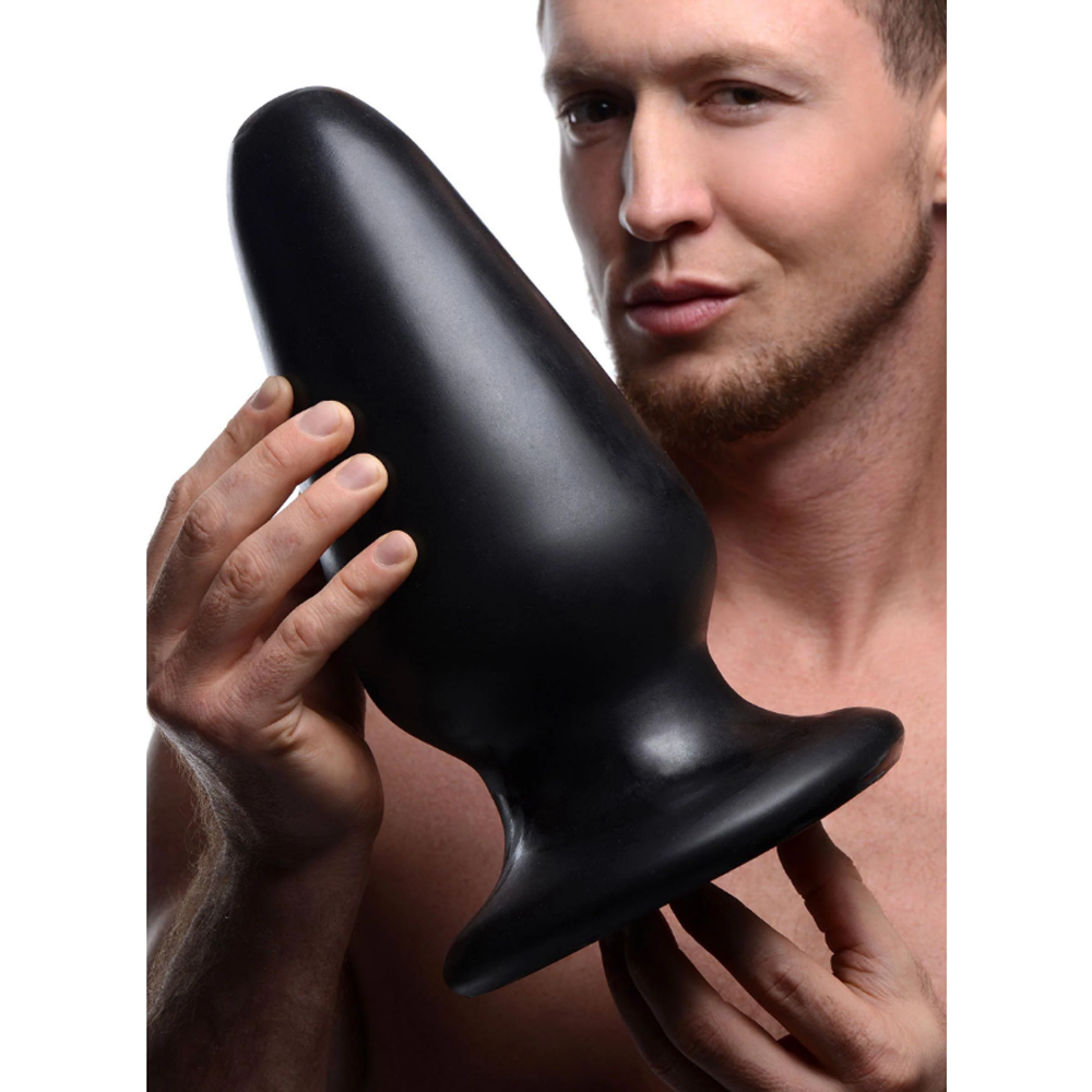 Black PVC Gigantor XXXL tapered anal plug held by a man.