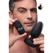 A man holds a black vibrating anal plug and its remote control.