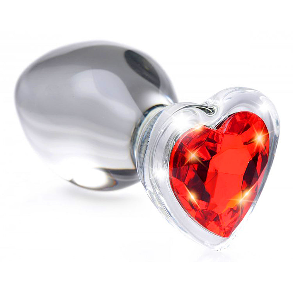 A clear glass anal plug with a red heart-shaped gem.