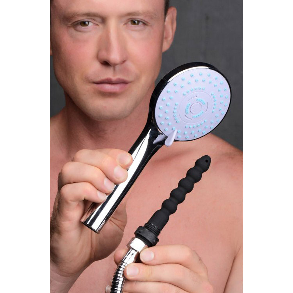 Man holding a shower head with a black silicone enema nozzle attached.