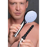 Man holding a shower head with a black silicone enema nozzle attached.
