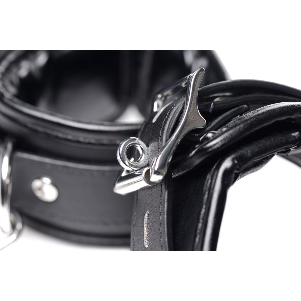 Black leather massage table with metal buckle and strap detail.