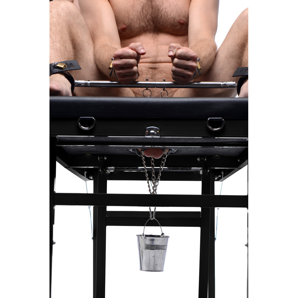 Bondage massage table with leather padding, cuffs, and a hanging bucket.