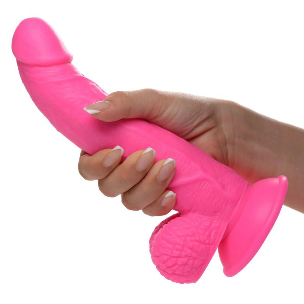 A pink 7.5-inch realistic PVC dildo with veiny shaft, balls, and suction cup base held in a hand.