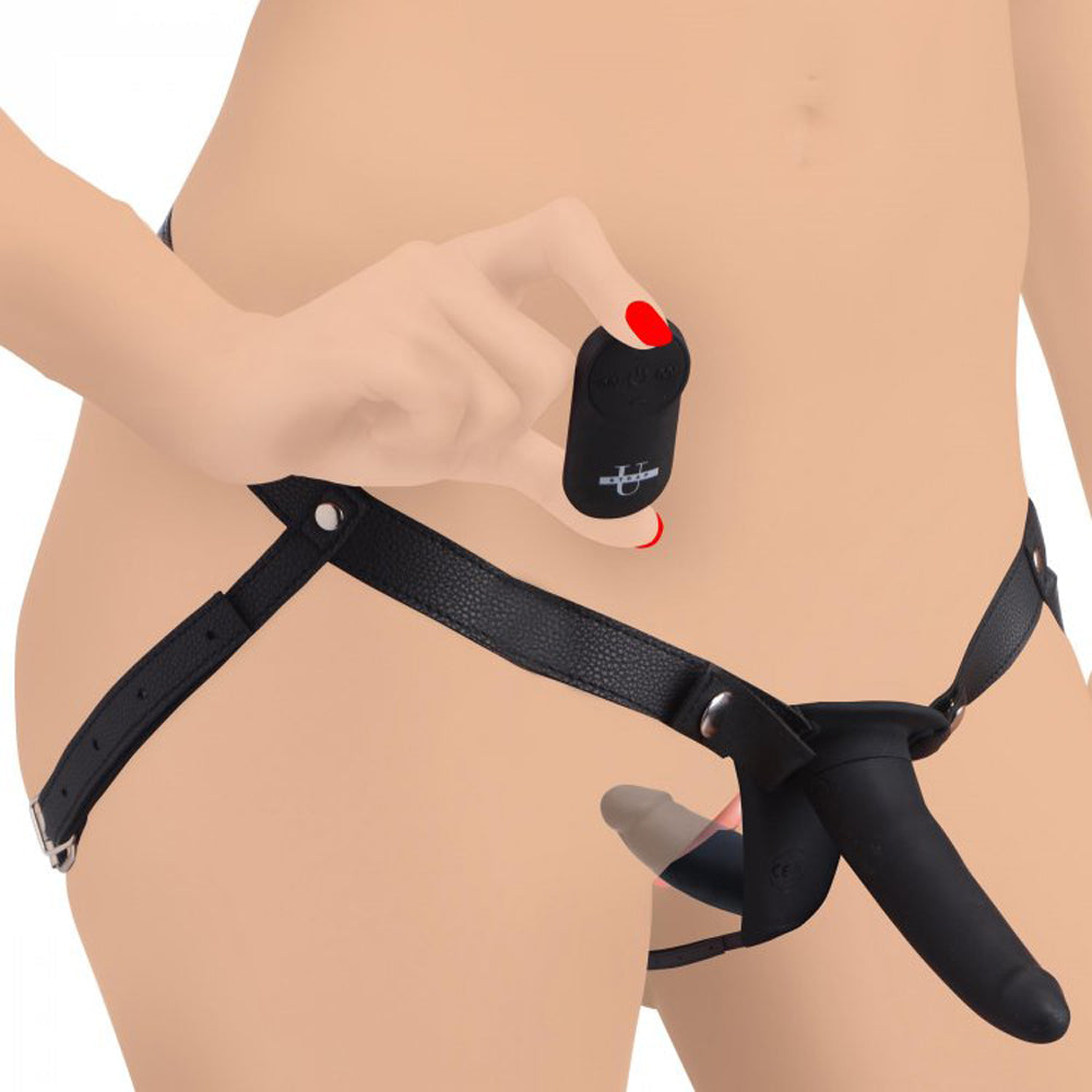 Black adjustable harness with remote-controlled vibrating double dildo for pegging.