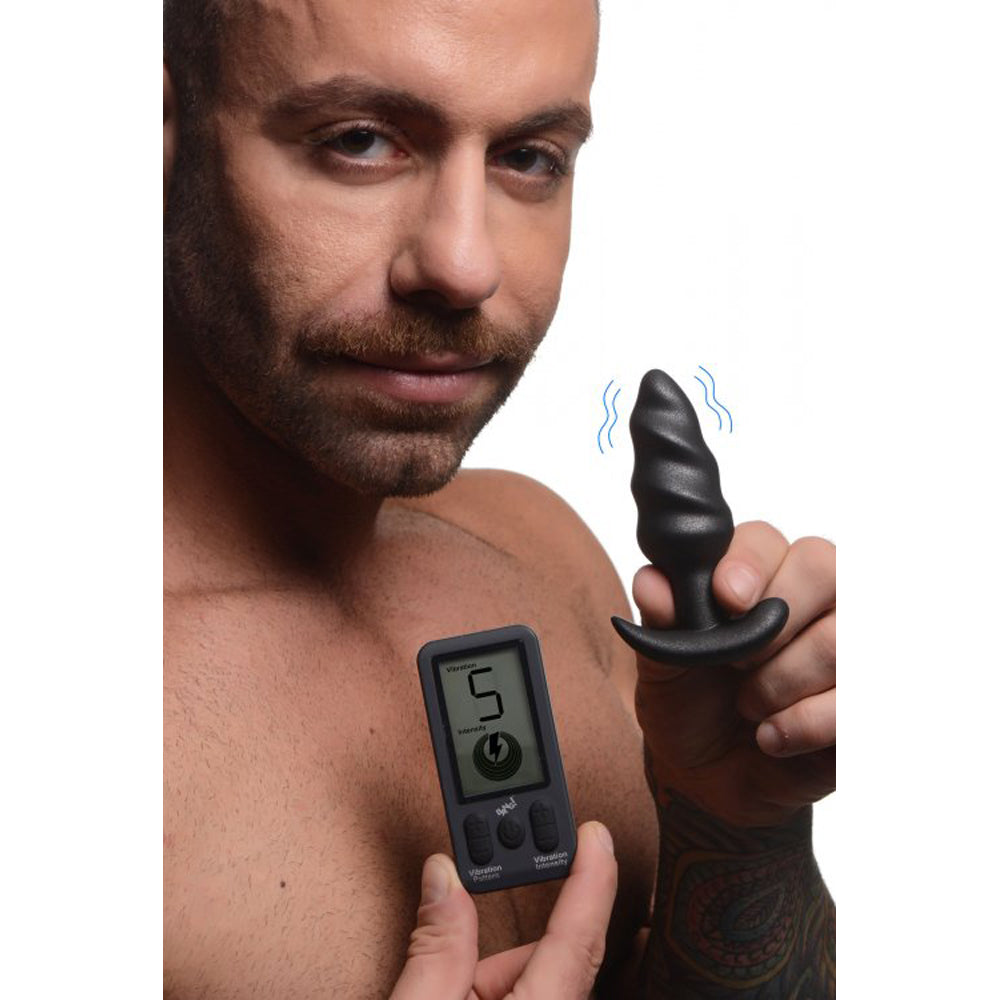 Man holding a black swirl vibrating butt plug and its remote control.