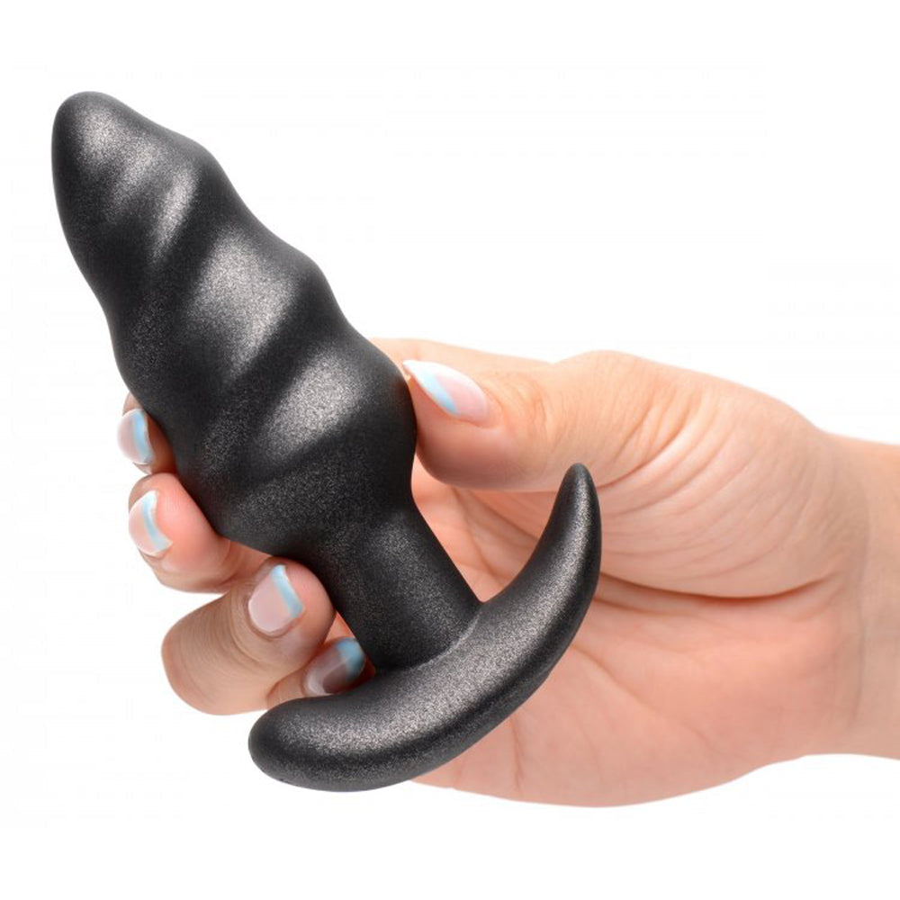 Black silicone swirl vibrating butt plug held in a hand.