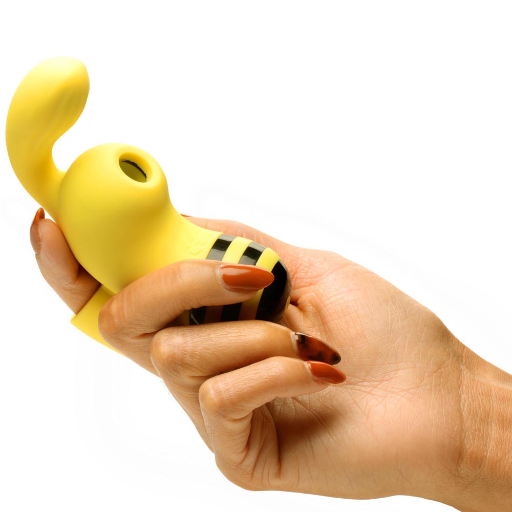 A yellow bee-shaped vibrator with black stripes held in a hand.