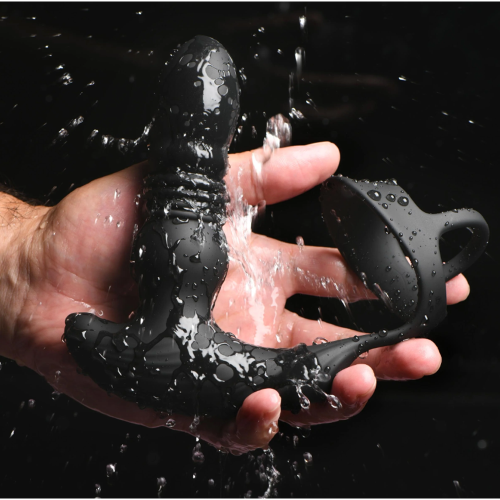 Black silicone anal plug with a cock ring, wet with water.