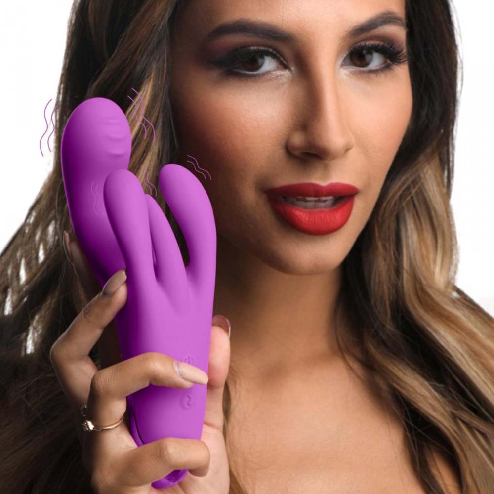 A woman holds a purple triple rabbit vibrator.