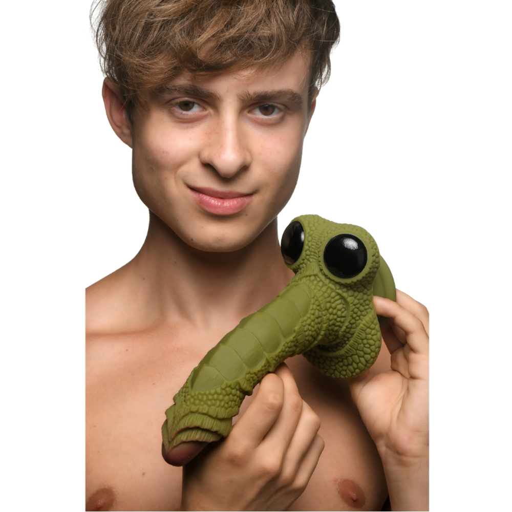 A green, scaly fantasy dildo with large black eyes and a textured shaft.