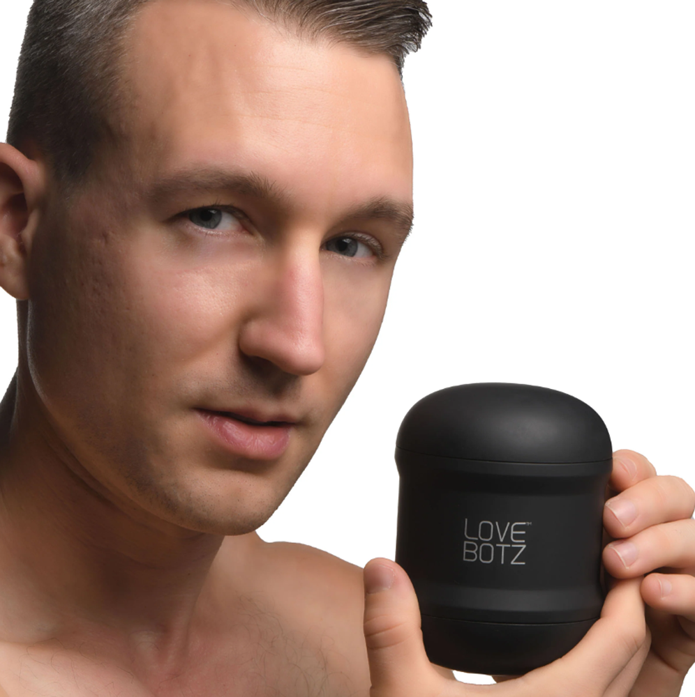 A man holds a black vibrating stroker with "LOVE BOTZ" printed on it.