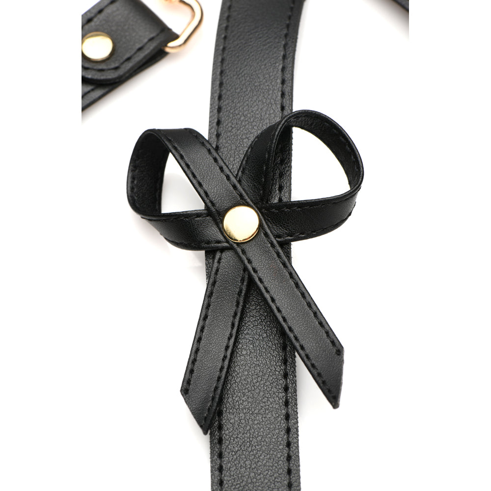 Black vegan leather harness with a bow detail and gold hardware.