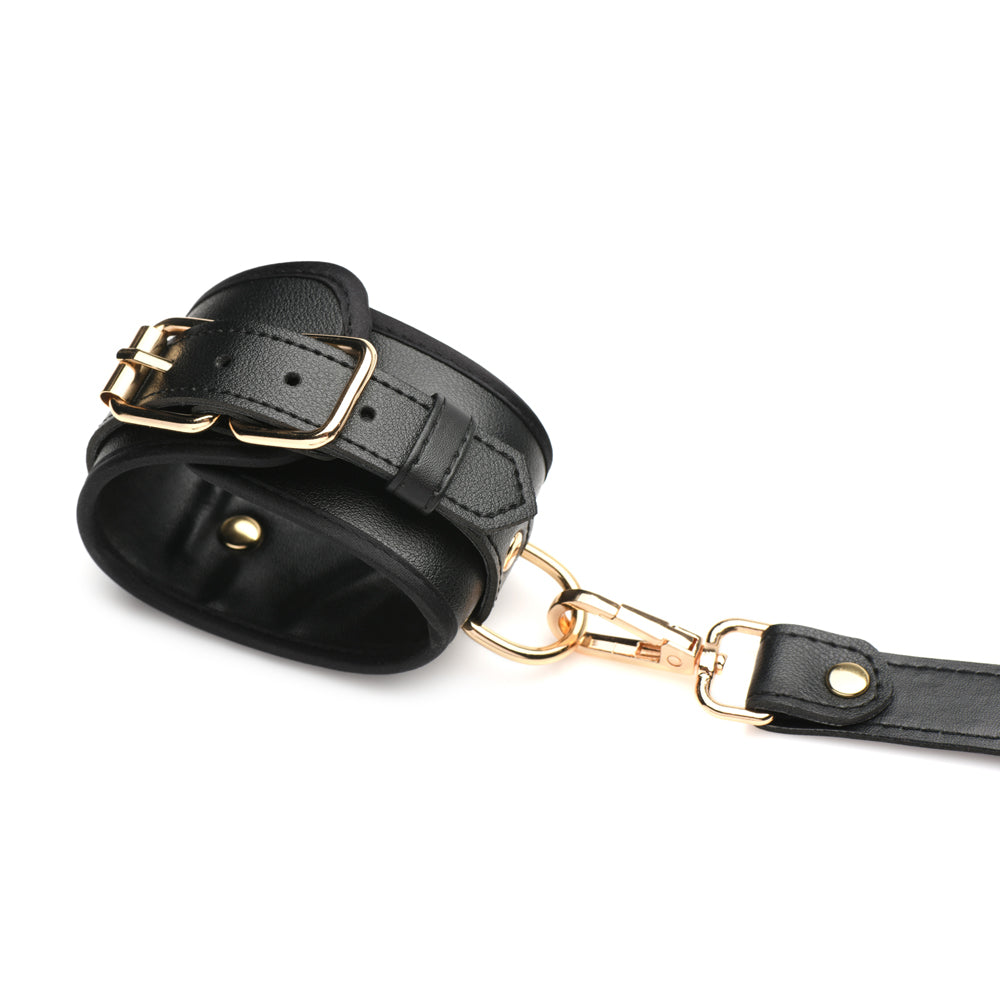 Black vegan leather wrist cuff with gold buckle and leash clip.