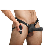 Man wearing black leather harness with vibrating silicone penis sheath and remote control.