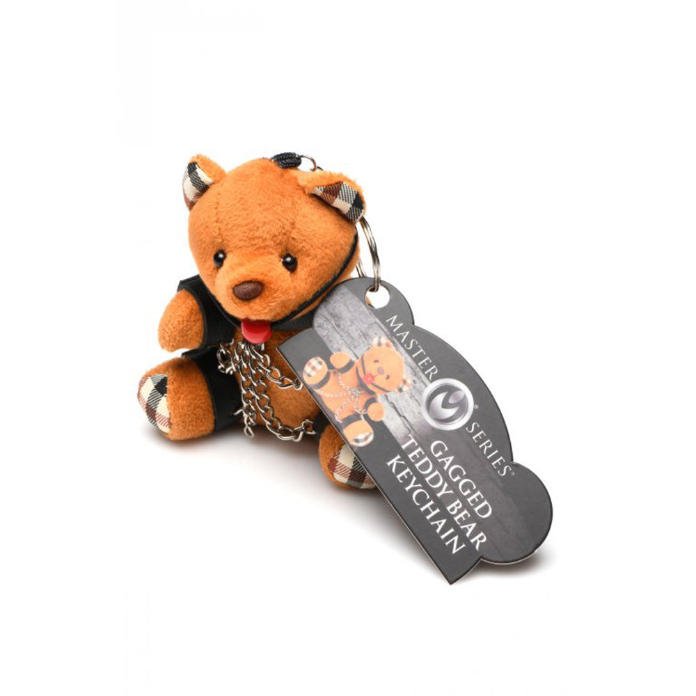 Burnt orange teddy bear keychain with a gag and chains.