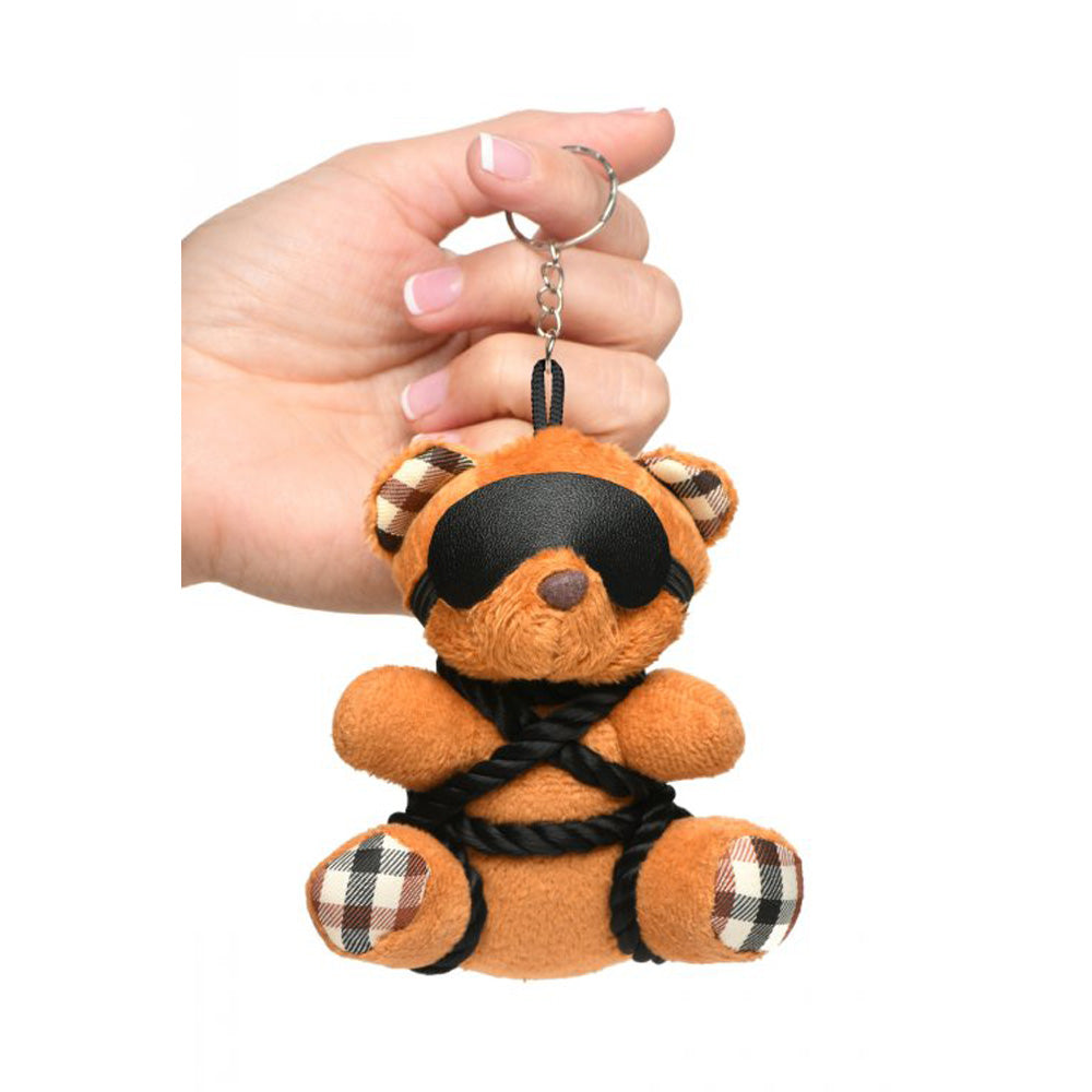 Burnt orange teddy bear keychain with black blindfold and rope ties.