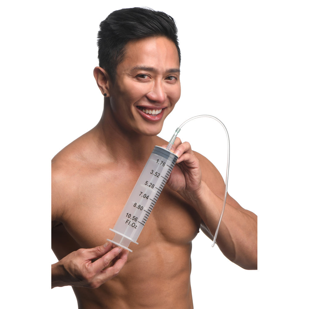 A man holds a large clear syringe with a flexible tube attached.