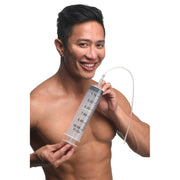 A man holds a large clear syringe with a flexible tube attached.