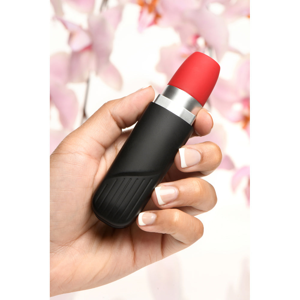 A hand holds a black and red lipstick-shaped clitoral vibrator.