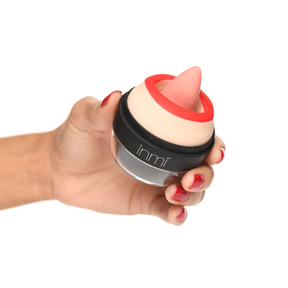 A hand holds a beige and red oral stimulator with the brand name "inmi" visible.