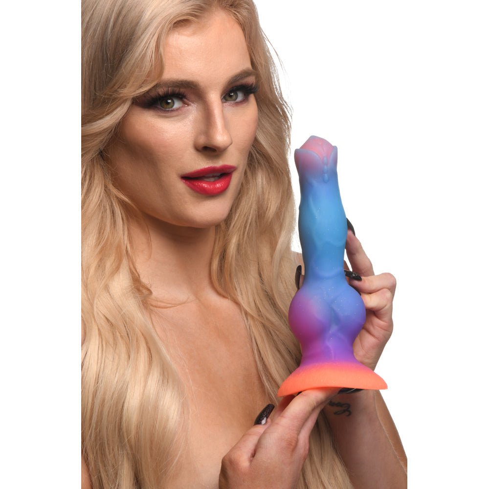 Blonde woman holding a glow-in-the-dark alien fantasy silicone dildo with suction cup base.