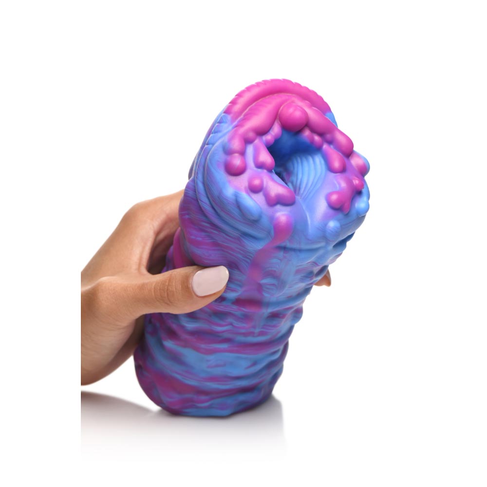 A hand holds a blue and pink textured silicone stroker.