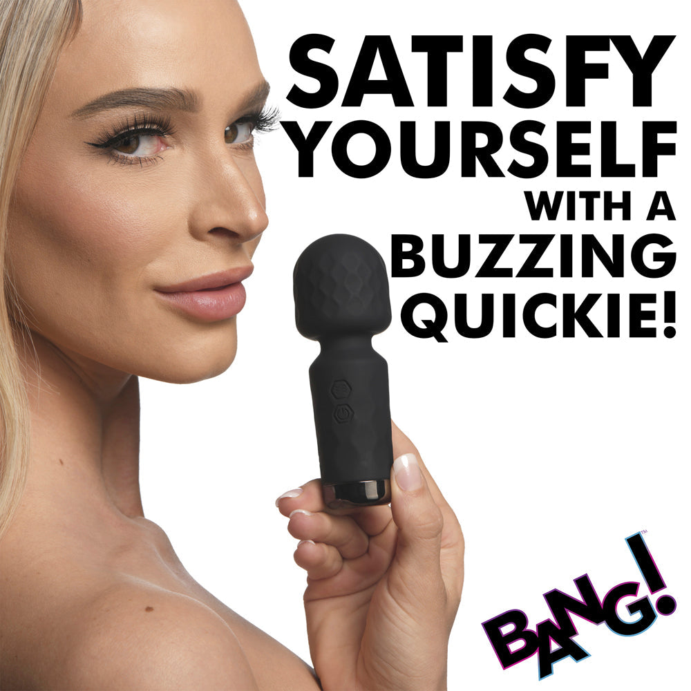 A black mini silicone wand vibrator held by a woman's hand.