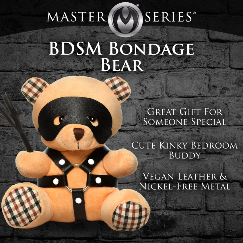A peach teddy bear wearing a black faux leather harness and eye mask, holding a mini flogger.