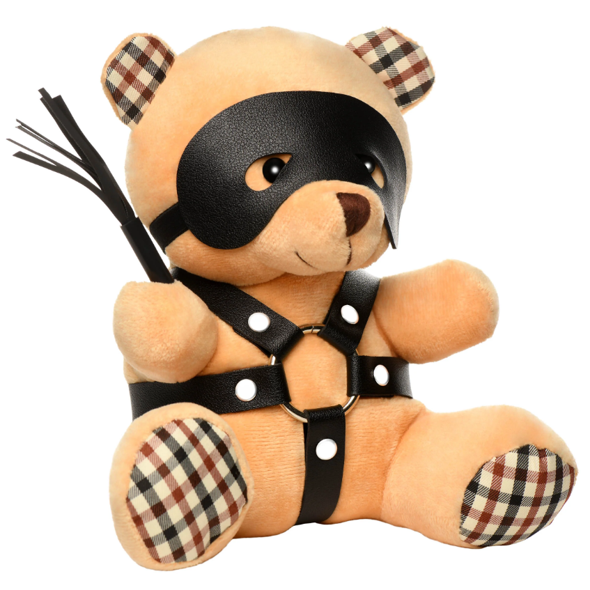 A plush teddy bear wearing a black faux leather mask and harness, holding a small whip.