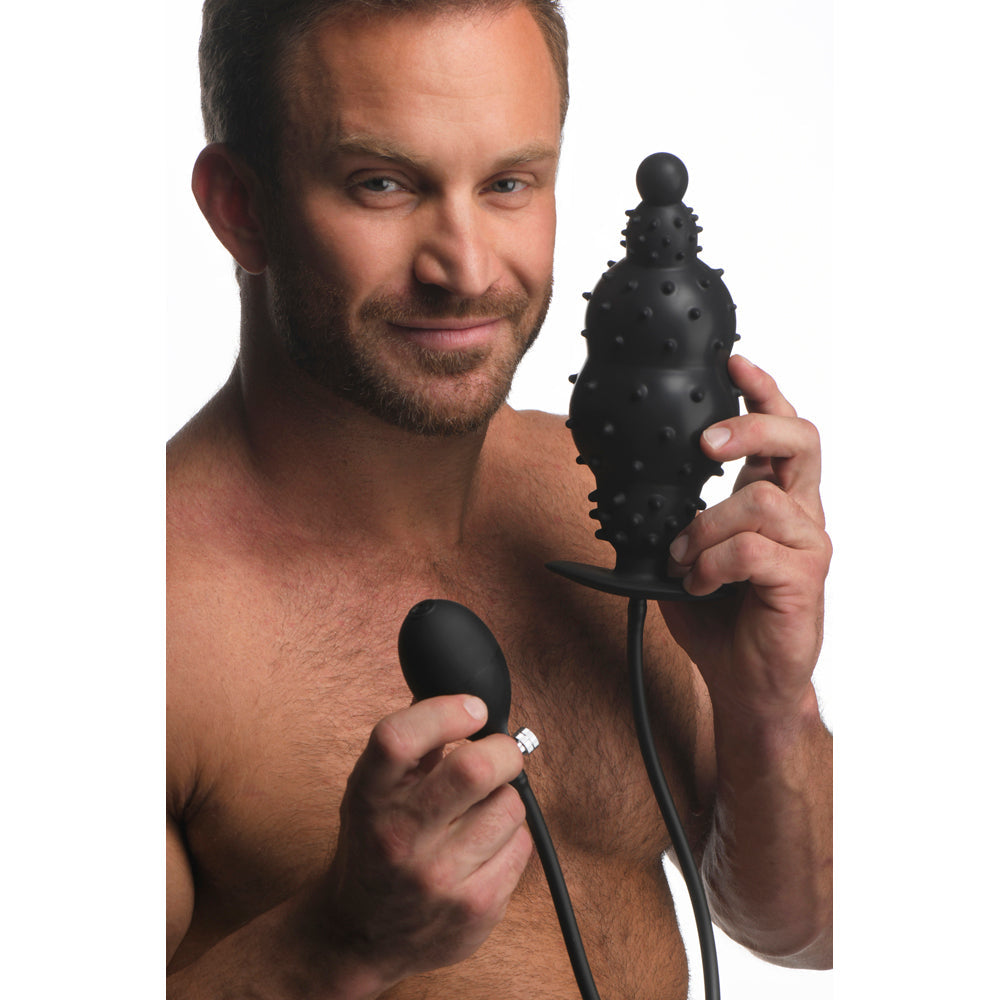 Man holding a black inflatable anal plug with nubs and a pump.