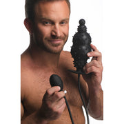 Man holding a black inflatable anal plug with nubs and a pump.