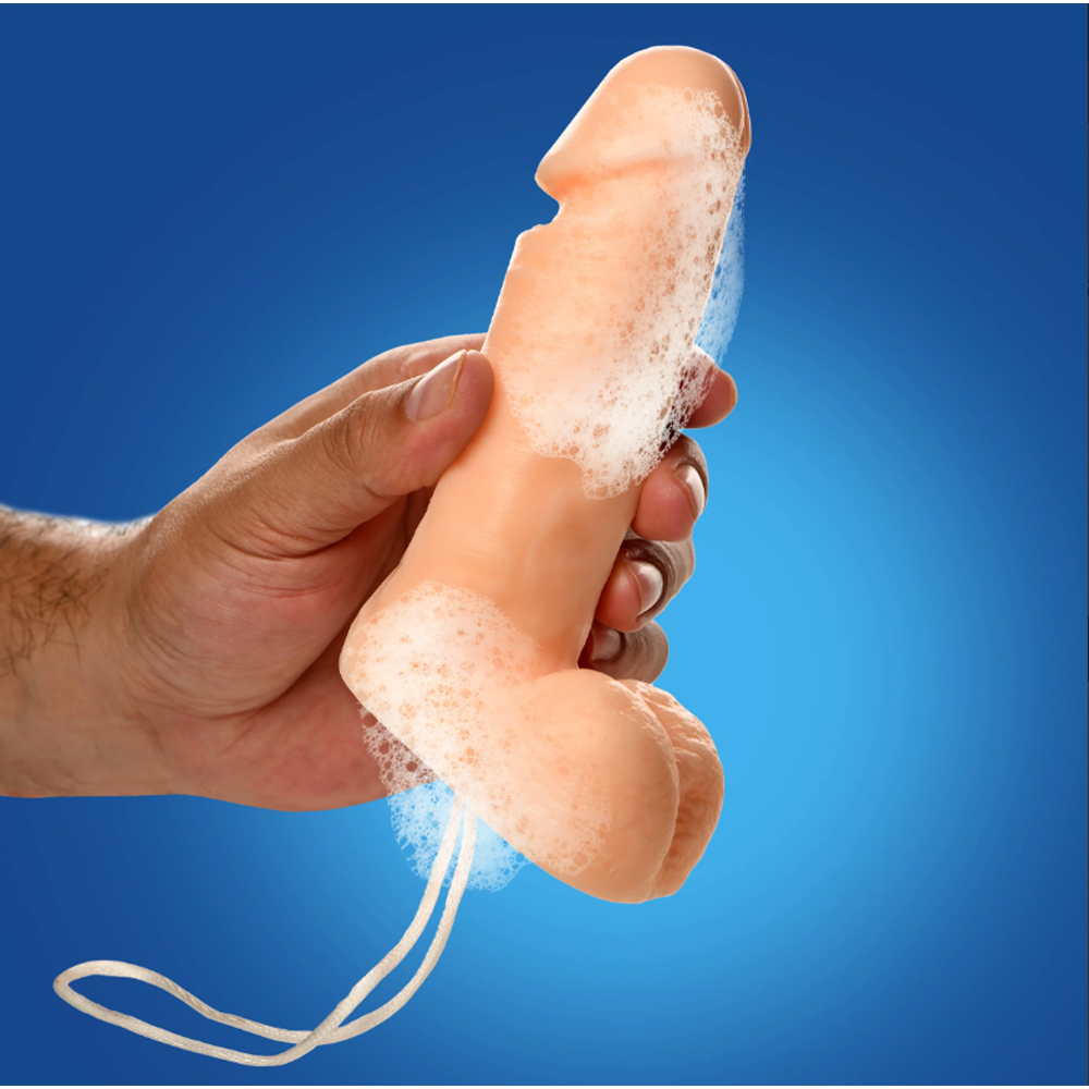 A hand holds a peach-colored penis-shaped soap bar with lather and a hanging rope on a blue background.