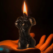 Black female torso candle with a flame held in cupped hands.